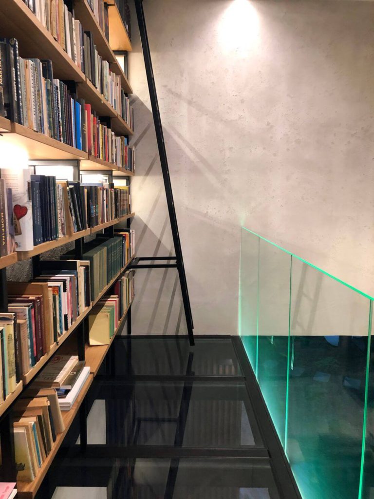 Szklana balustrada i drabina na antresoli loft metalowej z podłogą ze szkła hartowanego oraz biblioteką w stylu angielskim