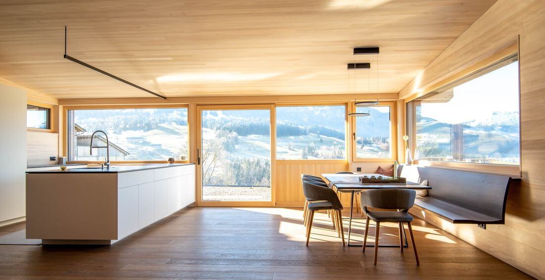 Loft-küche in einem Berghaus mit Insel und industriellem Holztisch - Industrieküche mit großen Fenstern